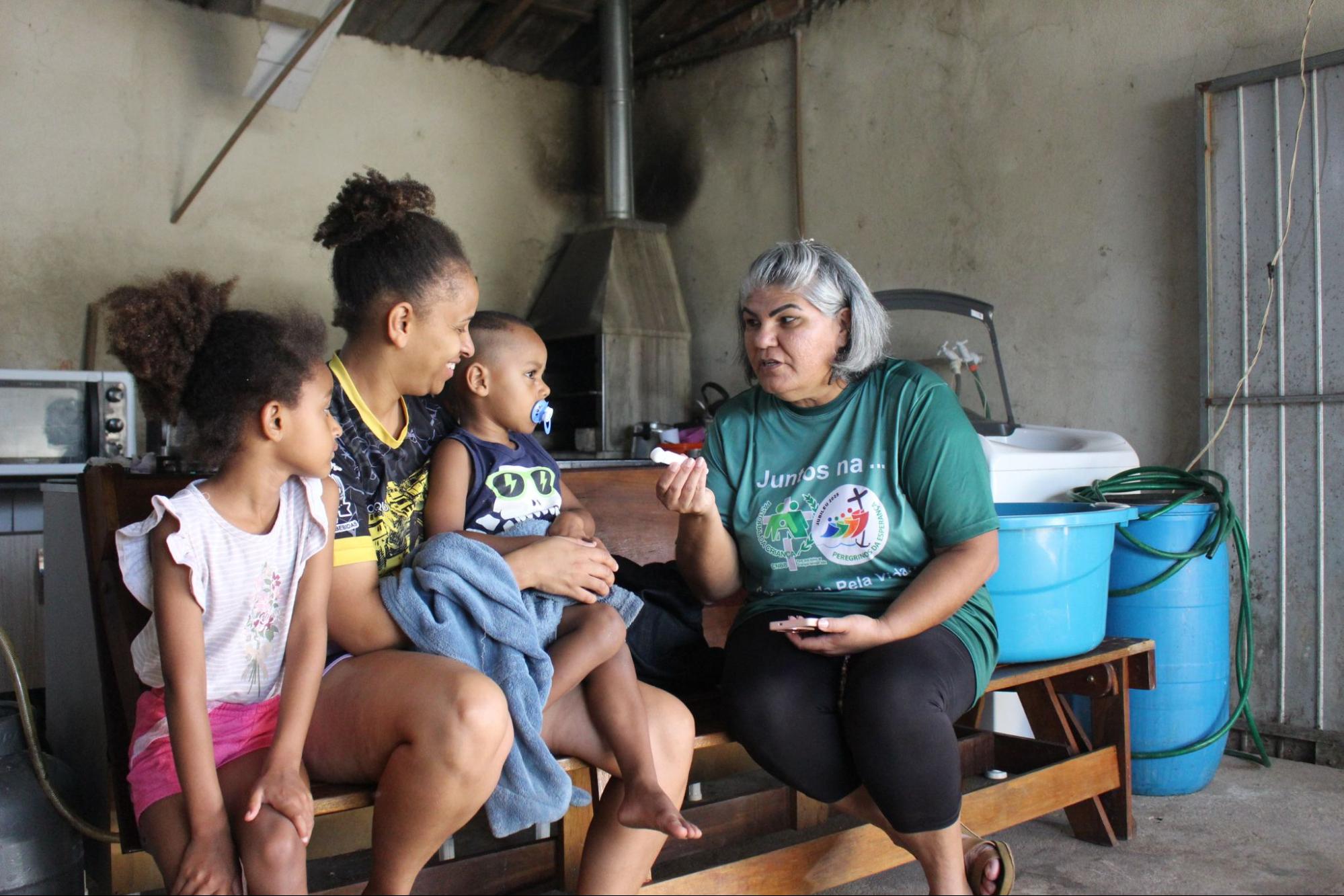Mãe e crianças recebem orientação de uma Líder da Pastoral da Criança